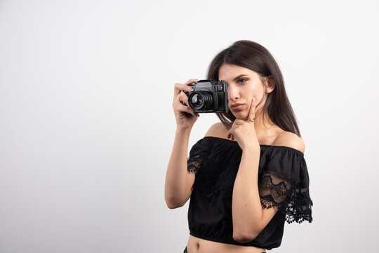 Brunette woman taking pictures with camera on white background