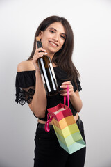 Young woman holding gift bag and wine on a white background