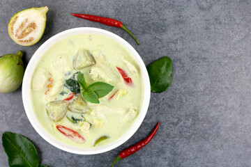 Green curry with chicken, basil, chili, lime leaf, eggplant on a grey background, top view. Popular Thai food.
