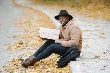 Black man hitchhiking on a road and holding a sign anywhere