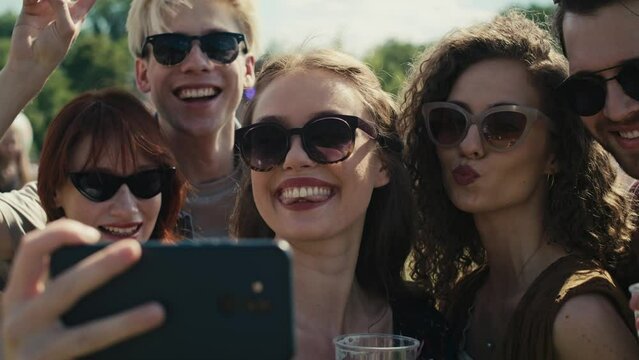 Group of caucasian friends making funny faces for a common selfie on music festival. Shot with RED helium camera in 8K. 