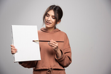 Naklejka premium Female painter posing with paint brushe and canvas