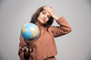 Brunette woman holding globe having troubles