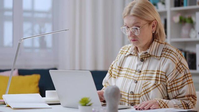 Senior woman working as financial analyst from home, experienced accountant