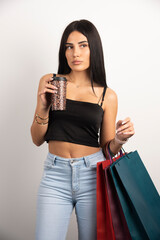 Brunette woman posing with shopping bags and coffee