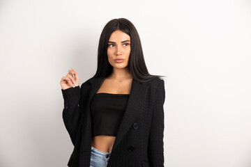 Brunette woman in black crop top standing on white background