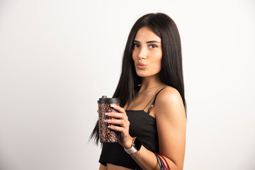 Portrait of woman holding cup of coffee on beige background