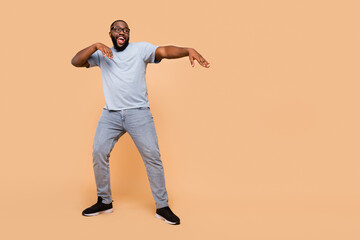 Fototapeta na wymiar Full length body size view of attractive cheerful guy moving having fun copy space isolated over beige pastel color background