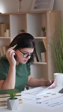 Vertical video. Statistics research. Data analysis. Financial review. Busy serious woman employee working with graphs charts at home office workplace.