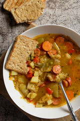 Vegetable soup with sliced Debrecziner sausages, a spicy Hungarian boiled sausage specialty. Top view.
