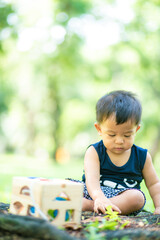 Toddler asian 2 year boy playing on green grass in nature park