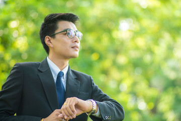 Naklejka na ściany i meble Business man wear black suit with glasses in green park