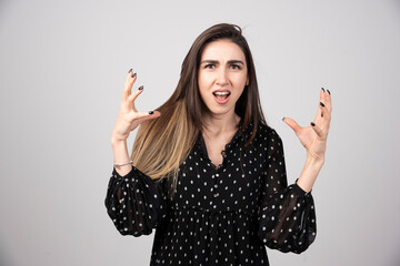 Woman in black dress getting angry on gray background