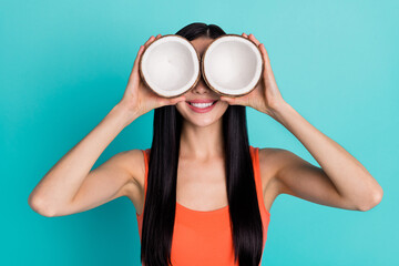 Photo of positive lady hide eyes face two sliced coco nut ripe holiday journey isolated cyan color...