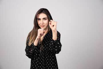 Portrait of woman showing her fists on gray background