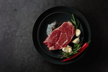 Raw beef meat steak with rosemary, garlic, salt, and pepper.