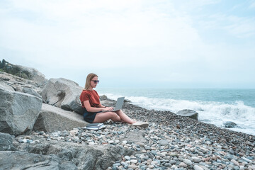 Remote work.Girl freelancer works remotely on the seashore.workation, remote work,WFVH,Van Life vibes work from vacation home,work travel,remotely work.Travelling