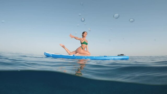 Girl does muscle relaxation on stand up paddle sup in ocean