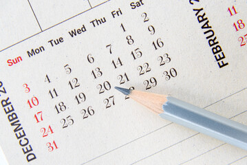 Calendar planner / timetable or schedule arrangement concept : Top view of a silver pencil on a...