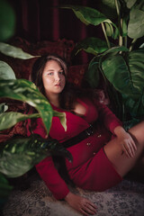 Obraz na płótnie Canvas Happy plus size woman with love tourself concept. Portrait of beautiful young woman in red clothes on the background of tropical plants. Overweight concept.