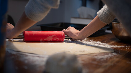Low angle view of a woman using rolling pin to roll homemade pastry dough