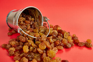 A small bucket filled with raisins on a red background.