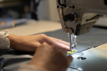Female seamstress hand working on sewing machine, sew clothes, closeup shot. Woman fashion collection designer create new garment. Tailoring hobby or professional occupation concept, Small business