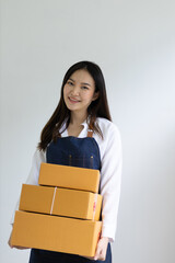 Portrait of a woman, a small start-up business owner working in a home office with parcel boxes for shipping online orders from the Internet.