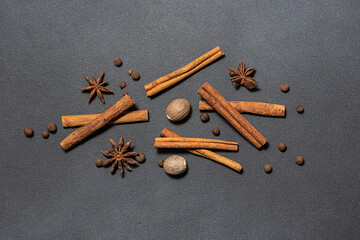 Set of spices for aromatic winter pastry and hot drinks. Cinnamon sticks, nutmeg, anise stars and allspice on black stone background top view.