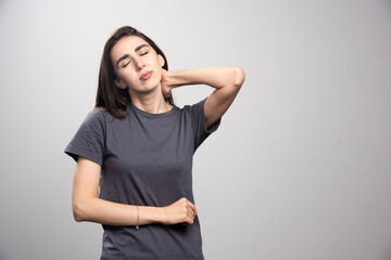 Image of a young pretty woman holding hand on neck