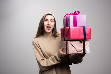 Young woman carrying three boxes of Christmas presents