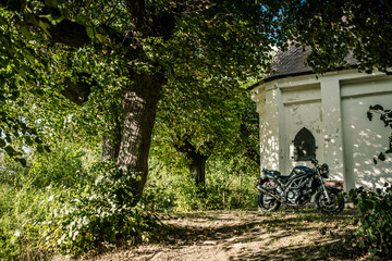 Motor zaparkowany pod kapliczką na wsi © Studio Migafka