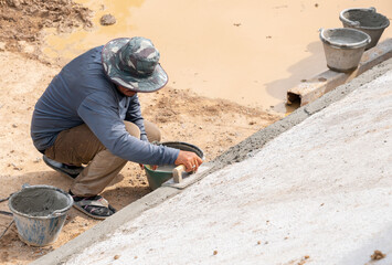 Workers use trowel plastering on the edge of the pool.