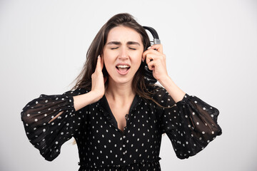 Young woman model listening music in headphones on a white background