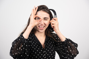 Fototapeta premium Young woman model listening music in headphones on a white background