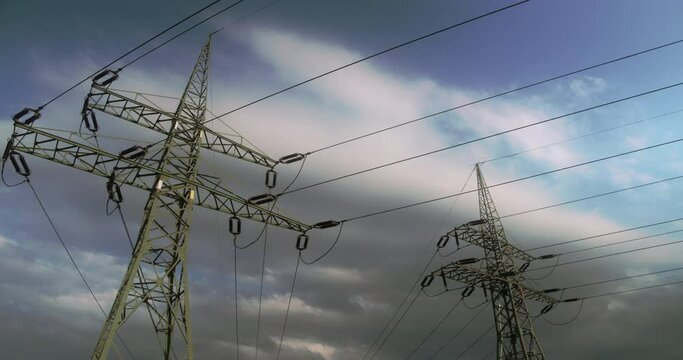 Timelapse. Floating clouds over high-voltage steel poles