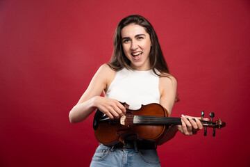 Young beautiful woman holding a violin on a red background