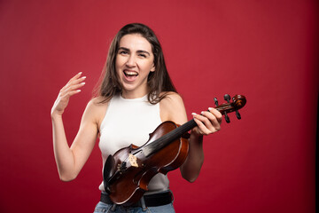 Young beautiful woman holding a violin on a red background