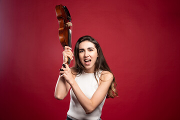 Young beautiful woman violin player on a red background