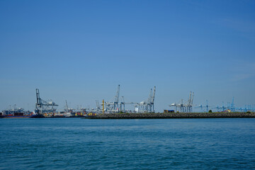 Fototapeta premium ROTTERDAM, THE NETHERLANDS - New container terminal with a very large container ship and in the foreground a smaller inland container ship on the Maasvlakte of the port of Rotterdam