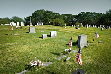White military headstone at burial sites with American Flags. Military cemetery with rows of...