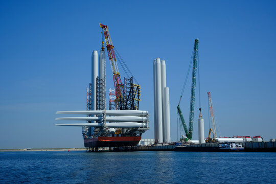 A large offshore vessel with a crane and a helipad is moored in the seaport of Rotterdam. A Jack-up vessel for use in the offshore wind industry