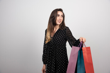 Fototapeta na wymiar Young woman model carrying a lot of shopping bags on a white background