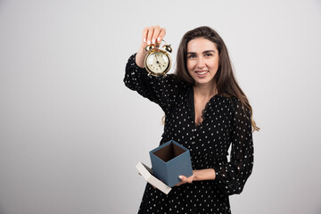 Young woman showing an alarm clock on a white background