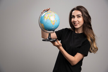 Happy woman holding globe on gray background