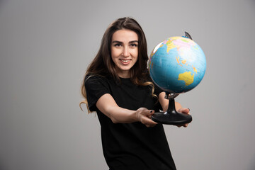 Happy woman holding globe on gray background