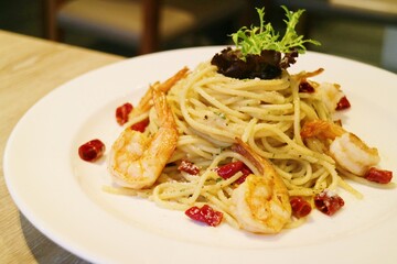 Seafood spaghetti with several prawns piled up like a hill on a white plate