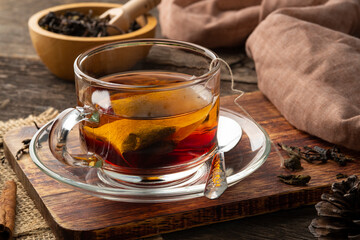 Black tea,Tea bag in hot water in glass cup on wooden table
