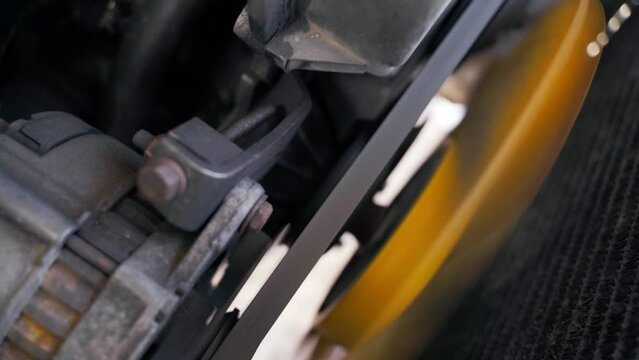 A yellow car engine cooling fan spins close-up near the radiator. car alternator belt