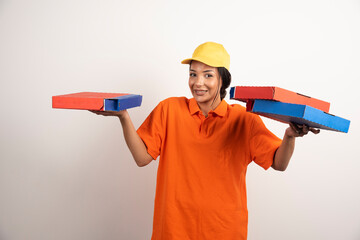 Woman courier in uniform holding bunch of pizzas